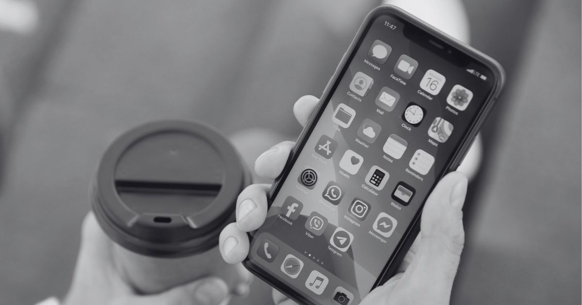 person holding phone and coffee cup