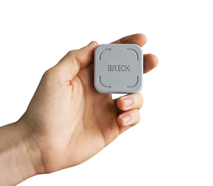 The Brick device in a hand showcasing the Brick. The Brick itself is square and the size of the palm of someones hand.