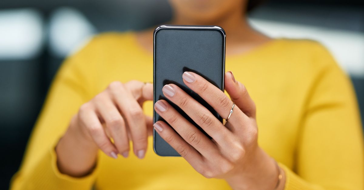 An up close shot of a woman's hands holding her phone, one finger scrolling to demonstrate that phone checking in constant in our lives.