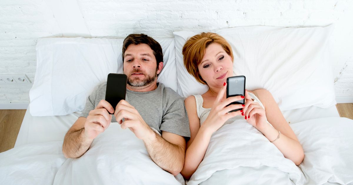 Man and woman lying in bed on screen that affect their relationship as they ignore one another.