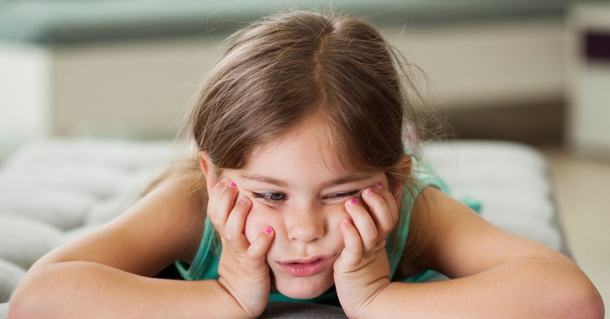 A bored little girl pouting because boredom and digital habits are connected.