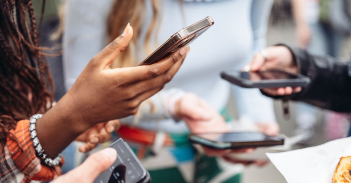 A picture with 4 people's hands and phones