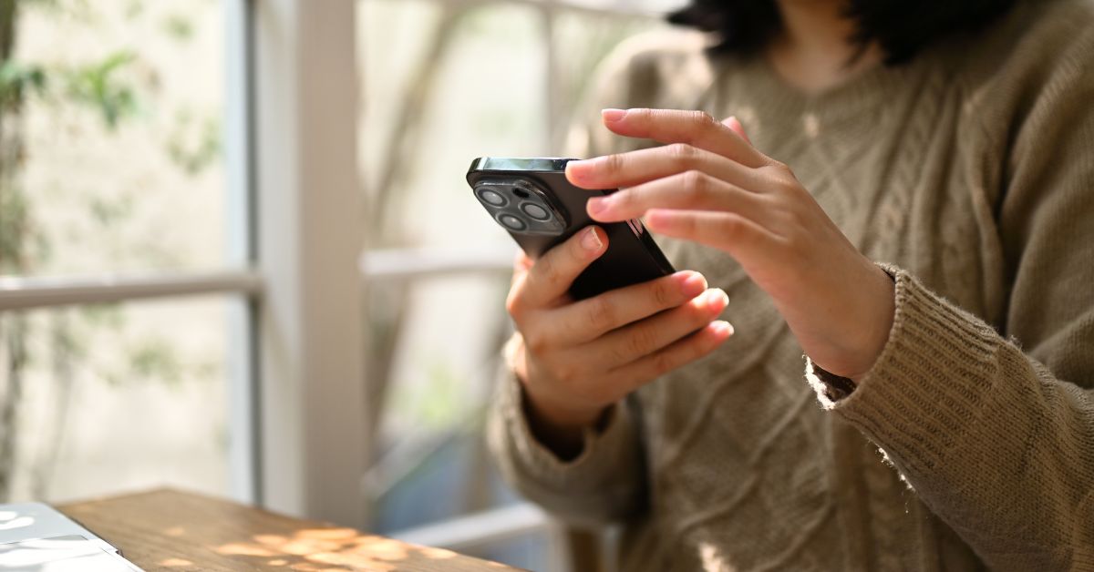 A woman's hands holding a phone with hands poised to scroll.